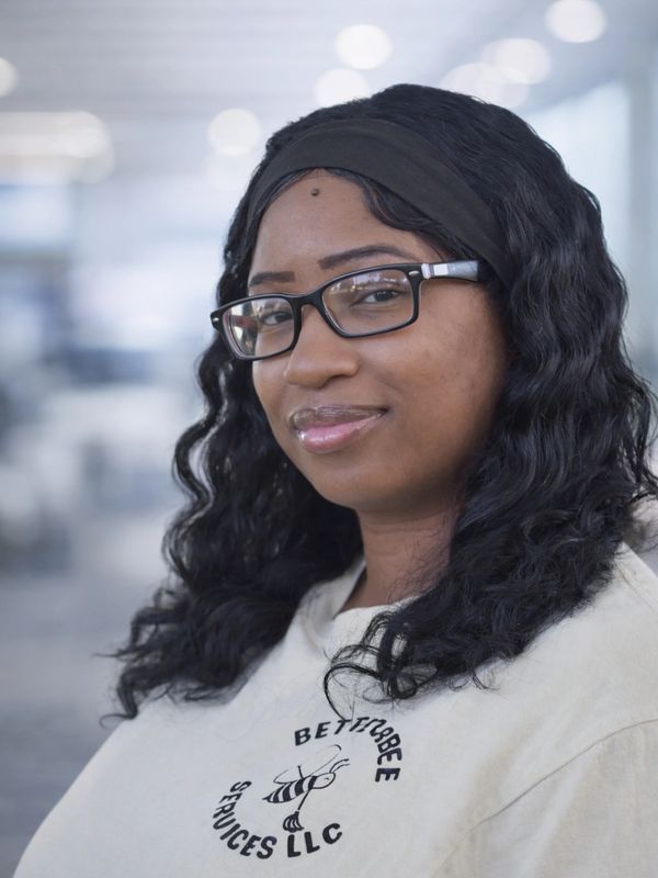 Woman with glasses and curly hair wearing a Betterbee Services LLC shirt.
