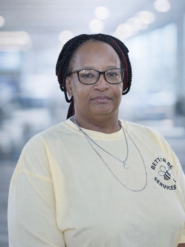 Woman with glasses wearing a yellow shirt in a bright indoor setting.