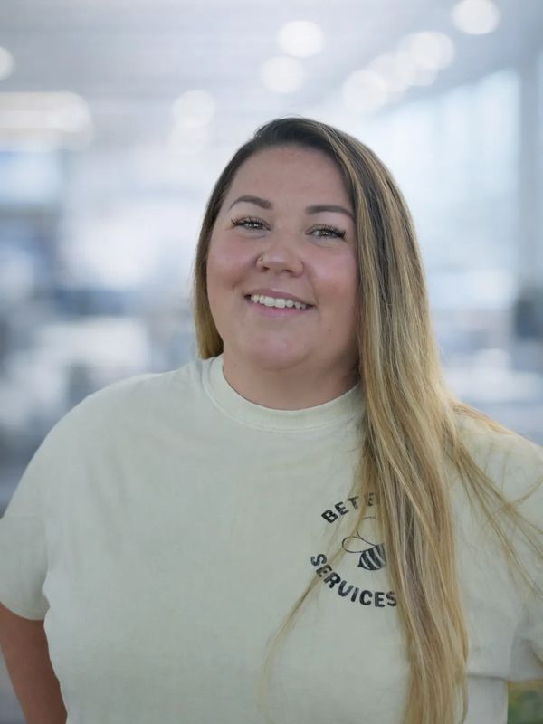 Smiling woman with long blonde hair wearing a light-colored t-shirt.