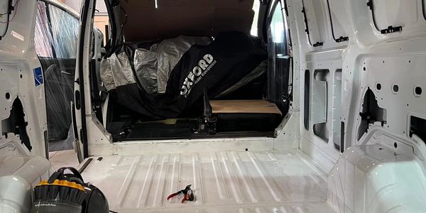 Empty white van interior with tools and covered items inside.