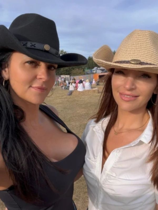 Two women wearing cowboy hats posing outdoors.