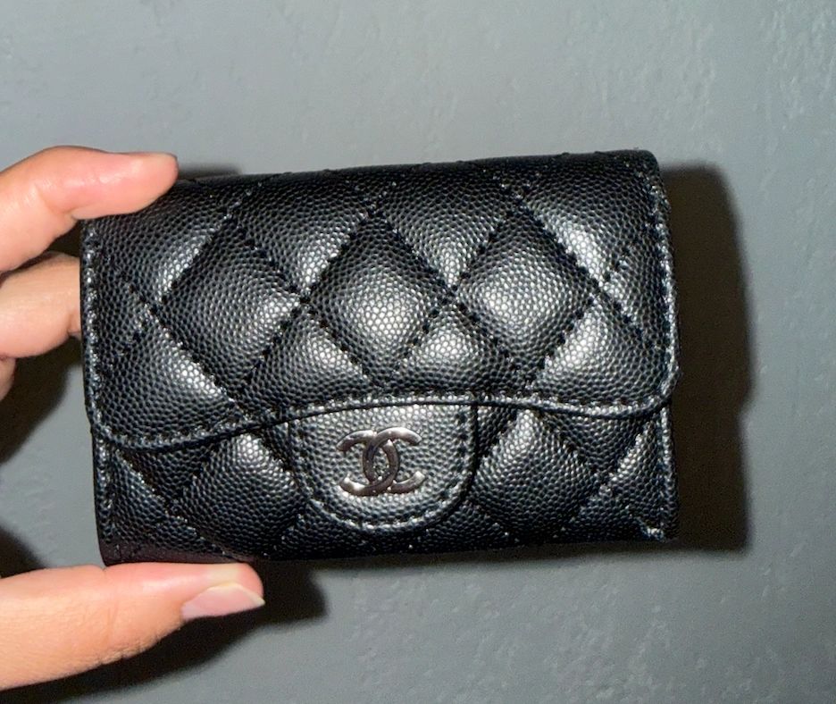 Black quilted Chanel wallet held by hand.