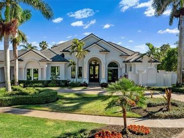 Elegant single-story house with manicured lawn and palm trees under a bright blue sky.