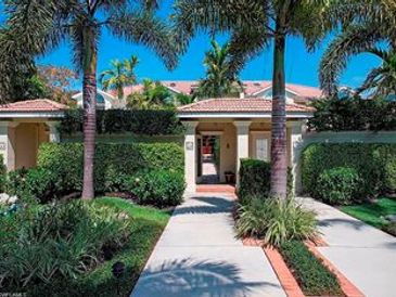 Entrance to a tropical-style house with palm trees and a tiled roof.