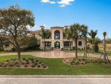 Large luxury house with manicured front yard and palm trees.