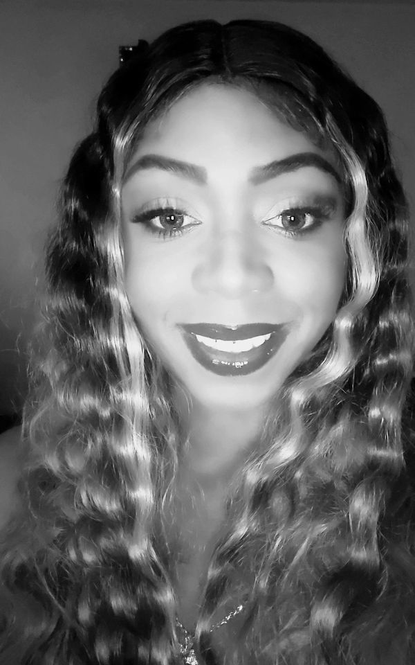 Smiling woman with wavy hair and makeup in black and white.