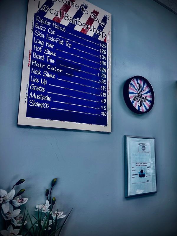 Above the workspace, a clock keeps time while the price board and business certificate hang nearby
