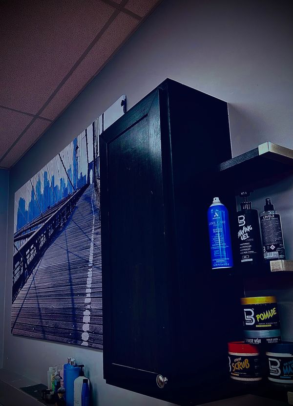 Next to the cabinet, a shelf displays hair products, and a framed picture adds a touch to the wall