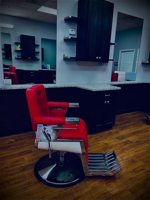 The chair sits ready for a cut, reflected in large mirrors above the organized cabinets behind