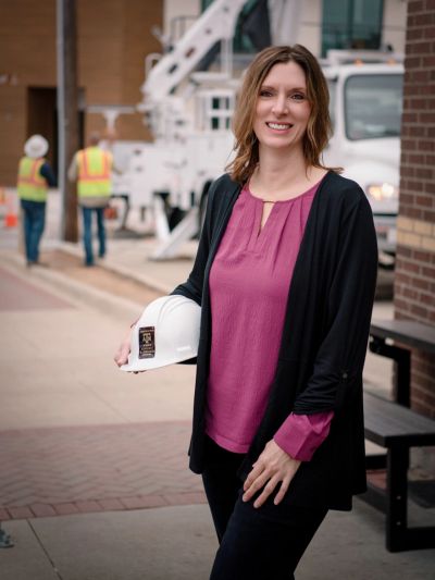 Kim Sheldon, proposal management consultant and founder of PROPOSALand, smiling and holding a hard h