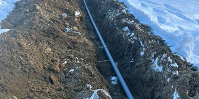 A trench with a pipe being installed in a snowy area.