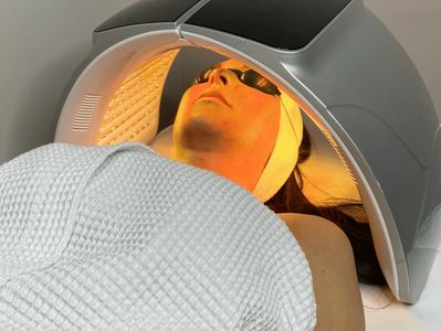 Person undergoing LED light facial therapy wearing protective goggles.