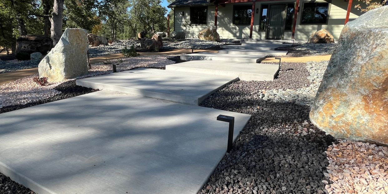Modern concrete walkway with geometric design leading to a house.