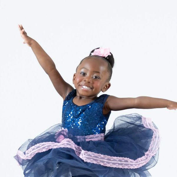 Happy young girl in a blue dress dancing.