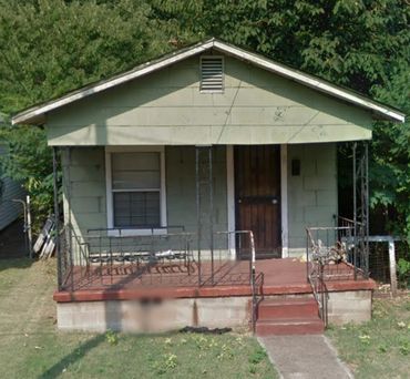 Small green house with front porch and metal railing.