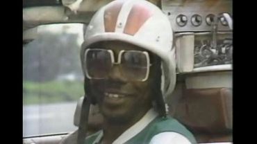 Man wearing helmet and sunglasses inside a vehicle.