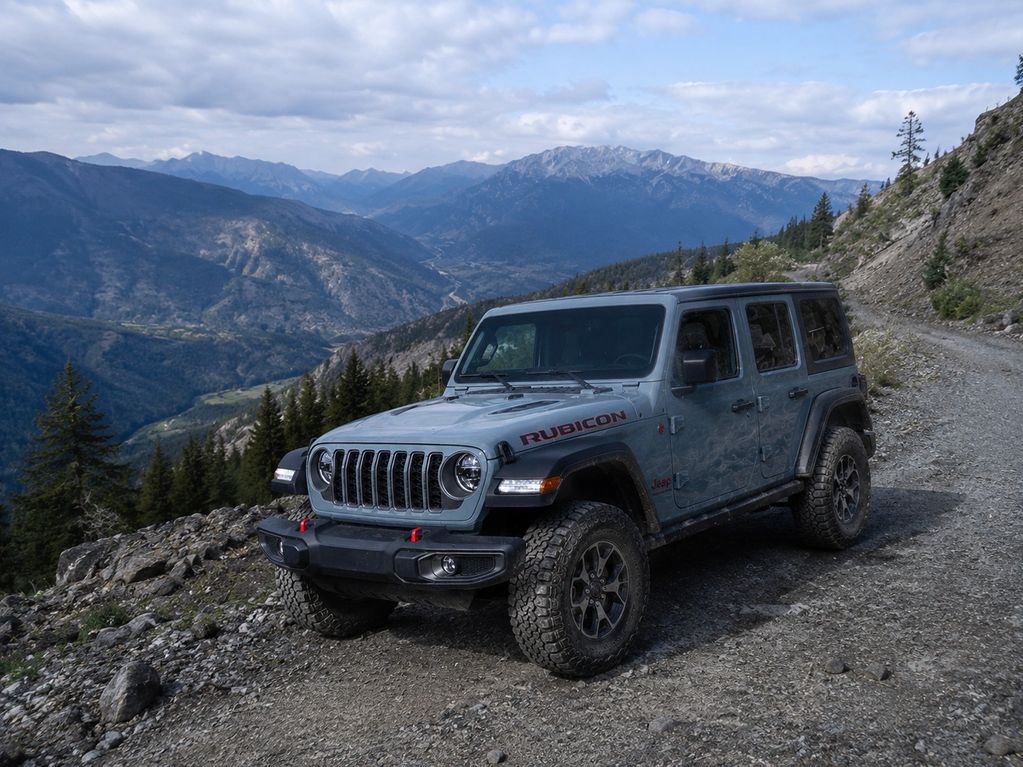 A Jeep Rubicon parked on a mountain trail with scenic views.