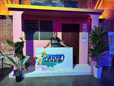 Person stands behind colorful DJ booth with 'BABBO' sign.