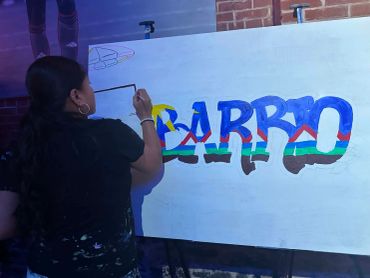 Woman painting colorful letters on a canvas.