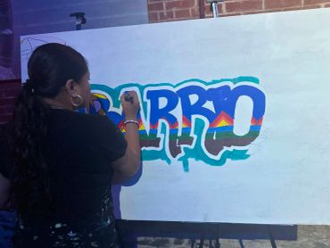 Woman painting colorful graffiti on white canvas.