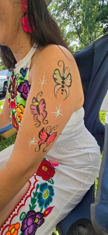 Woman with colorful butterfly tattoos on her arm.