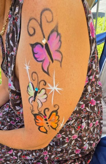 Colorful butterfly tattoo on arm with sparkling accents.