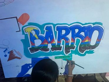 Person painting colorful graffiti that says 'Barrio'.