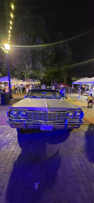 Classic car displayed at night event with blue lights.