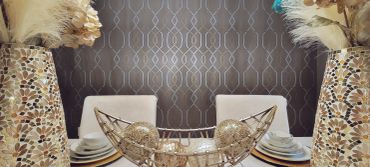 Decorative dining table centerpiece with art vases and textured wallpaper.