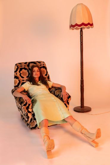 Woman relaxing in a retro chair next to a vintage lamp.