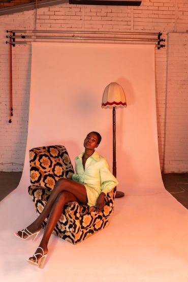 Woman in a green dress sitting on a patterned armchair.