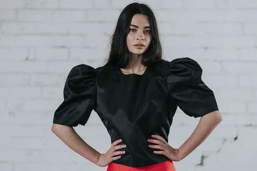 Woman wearing black puff-sleeve top and red skirt.