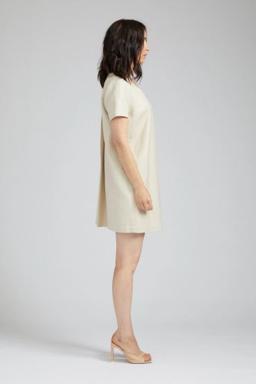 Woman in a beige dress and nude heels, side view.