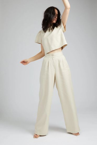 Woman in beige wide-leg pants and cropped top.
