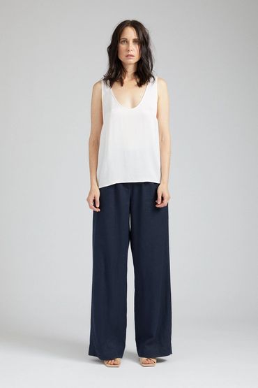 Woman wearing a white sleeveless top and navy wide-leg pants.