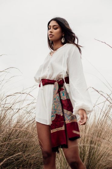 Woman in white dress with red scarf in a natural setting.