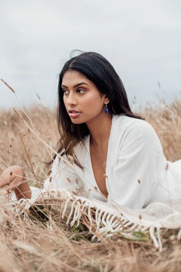 Woman lying in dry grass wearing a white outfit.