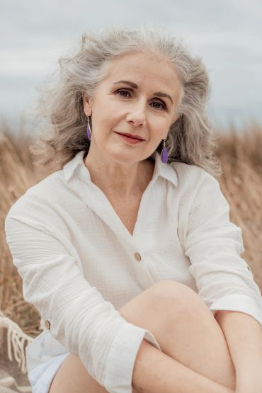 Calm older woman with gray hair sitting outdoors.