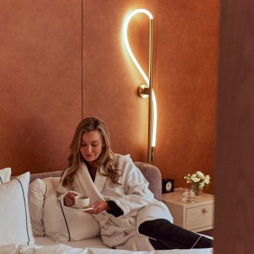 Woman relaxing in a cozy room with a modern lamp.