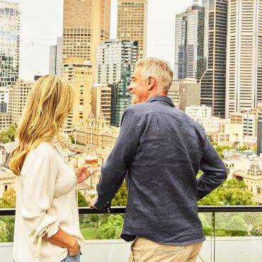 A couple enjoying drinks on a city rooftop with skyscrapers.