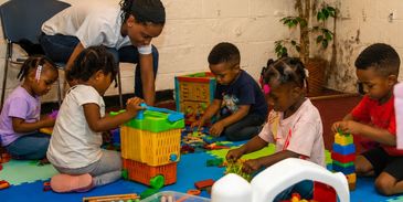 Children playing with toys under adult supervision.