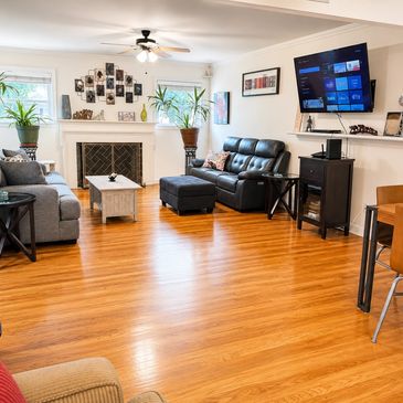 Cozy living room with wooden floors, black leather sofa, and wall-mounted TV.