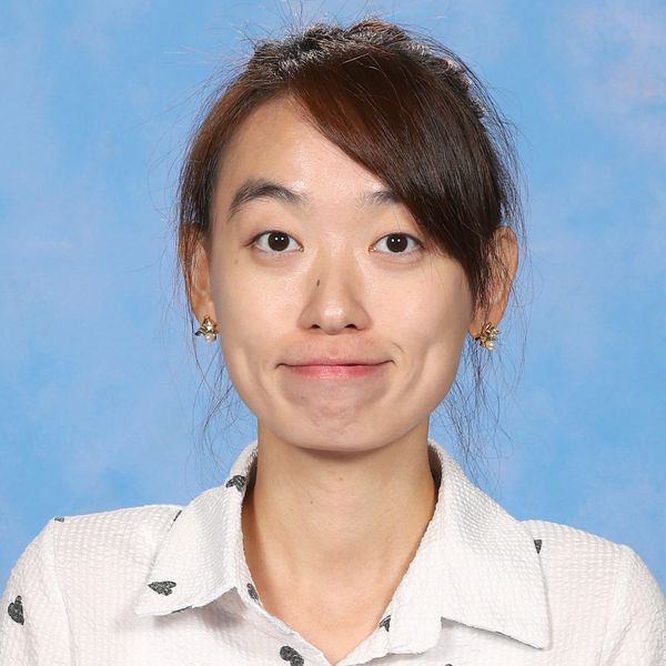 Portrait of a woman with a subtle smile wearing a white shirt with black hearts.