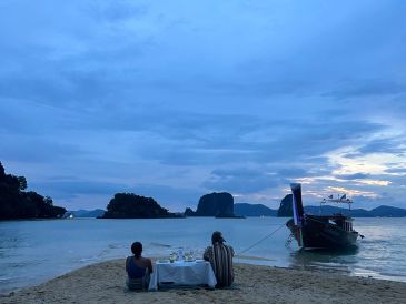 คนสองคนทานข้าวริมหาดกับเรือในทะเล