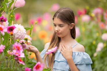 11 year old girl looking at beautiful display of brightly colored  flowers in the park.