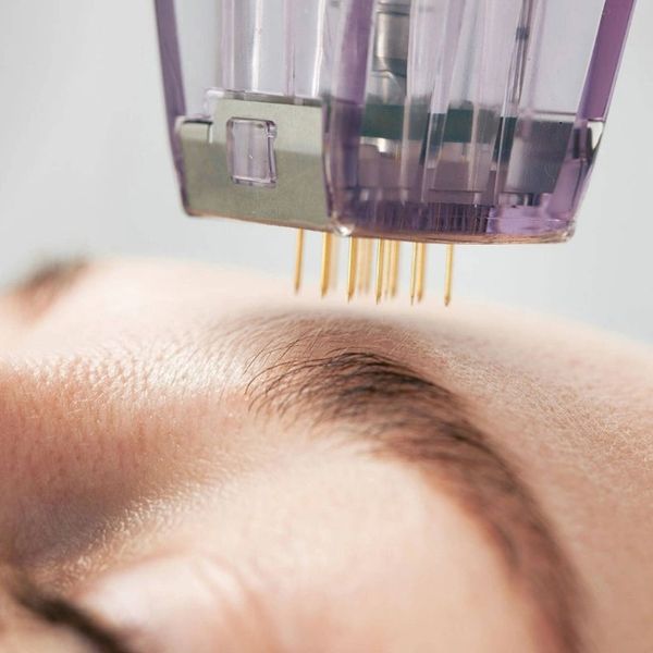 Woman using microcurrent device for facial toning and anti-aging.

