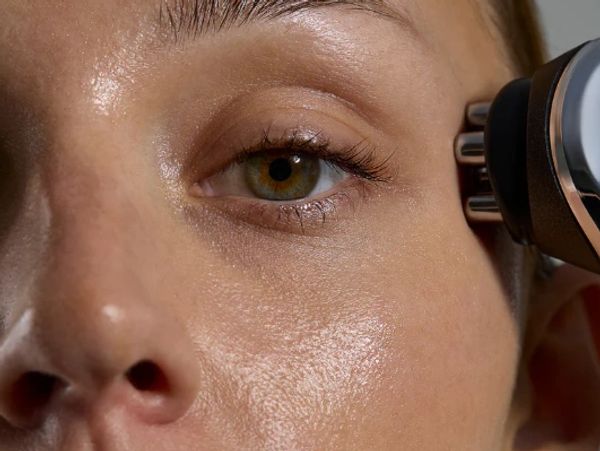 Close-up of a woman using a microcurrent facial device on her face.