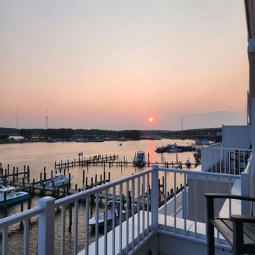 Sunset view over a marina from a balcony with boats docked.