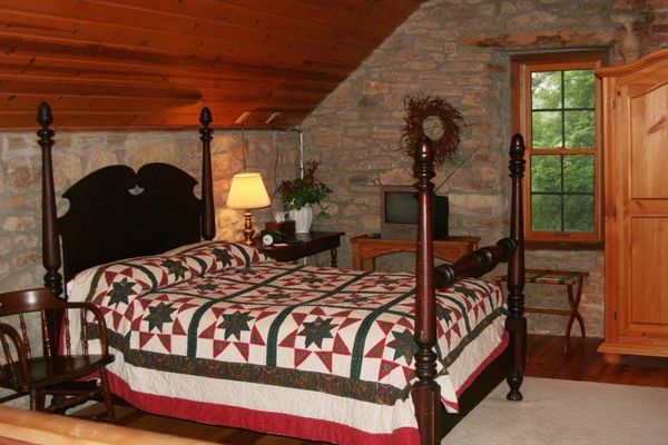Cozy rustic bedroom with a wooden four-poster bed and quilt.