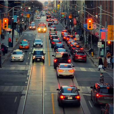 Busy urban street with cars waiting at a red light during evening rush hour.